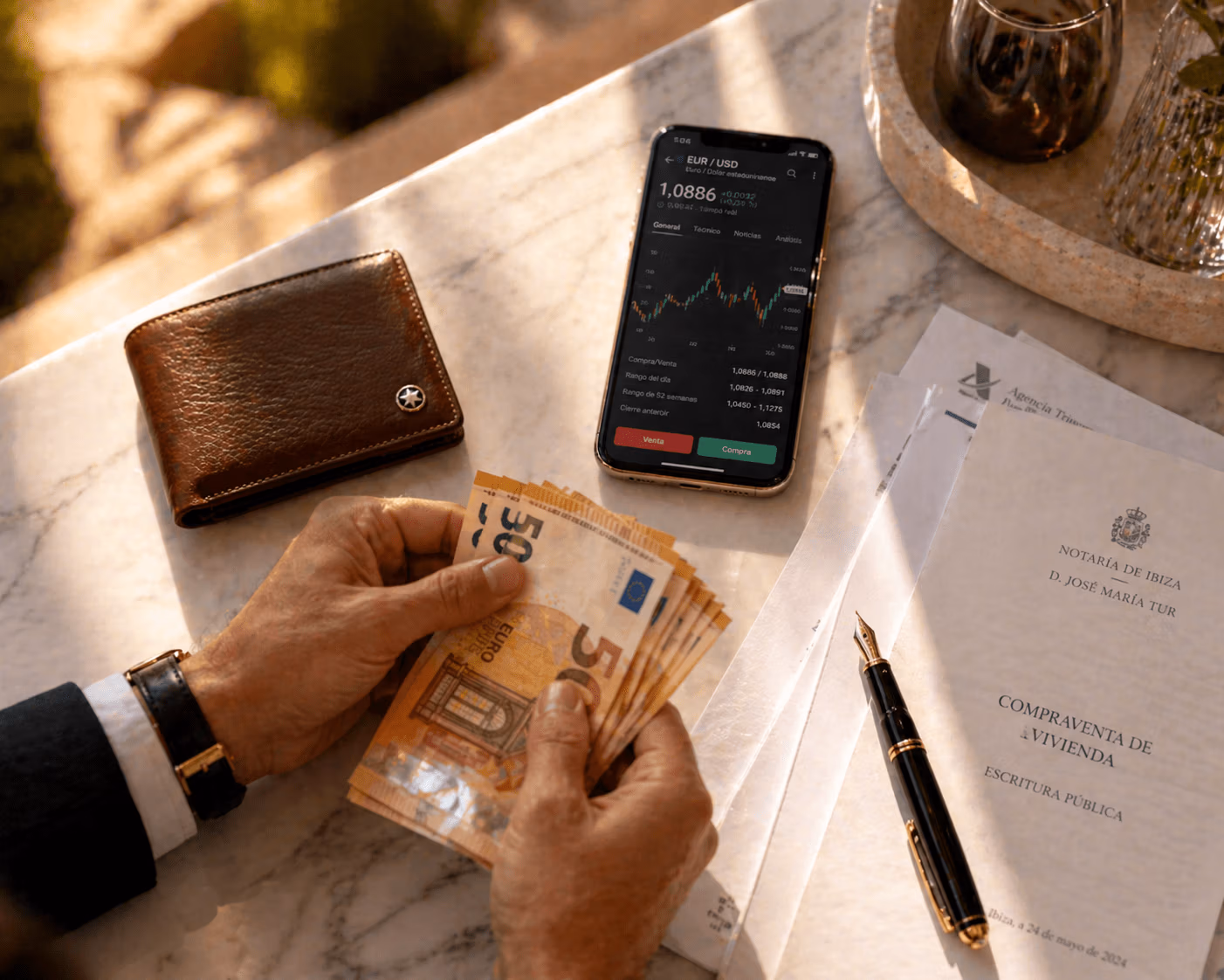 Crisp Euro banknotes beside a smartphone showing a live exchange-rate chart on a marble desk